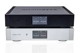 Boîtier hi-fi haut de gamme noir empilable avec affichage numérique, posé au-dessus d’un modèle blanc identique, sur fond blanc.